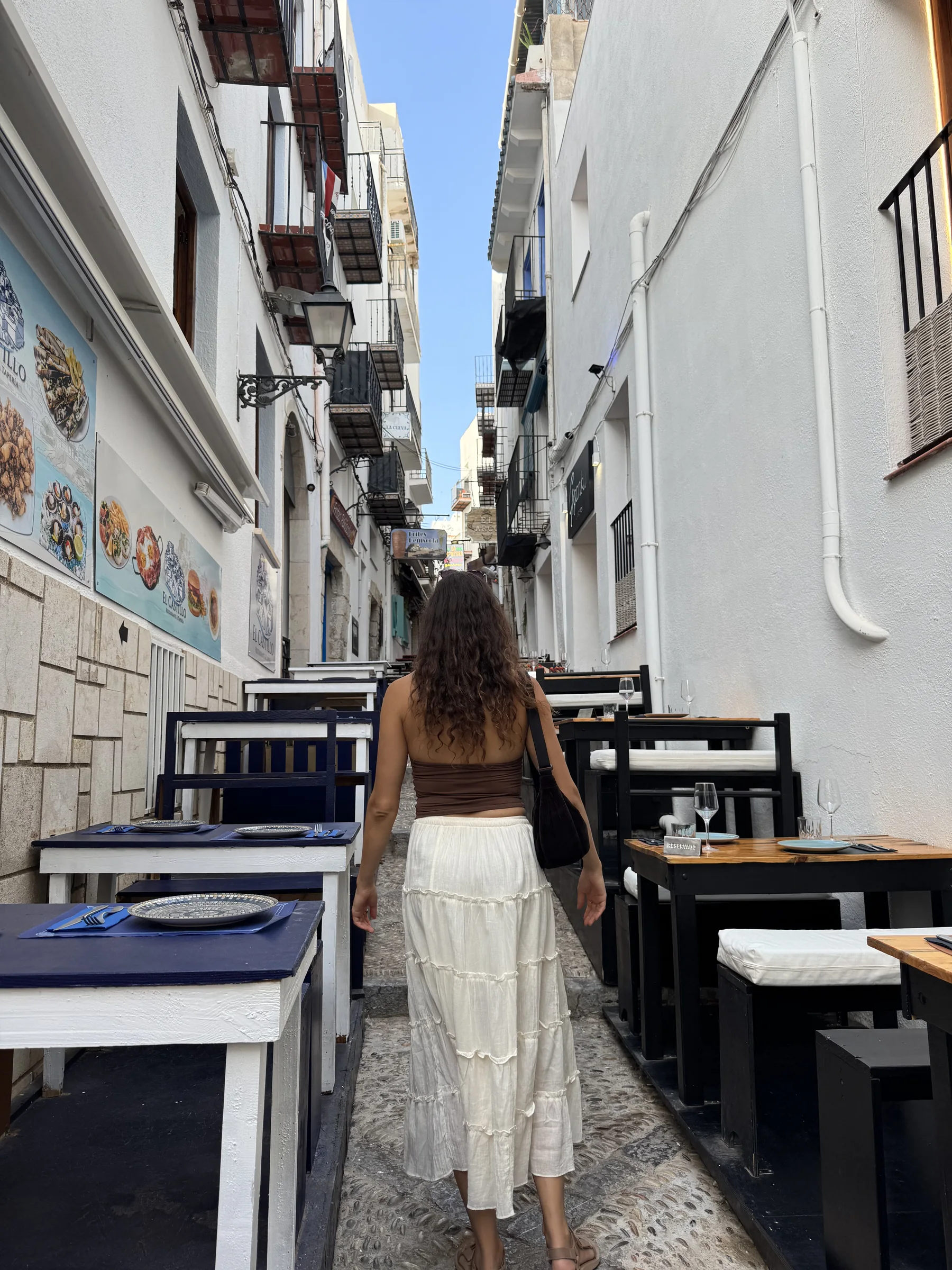 Ein Reisender geht durch eine schmale, von Restaurants gesäumte Gasse in der Altstadt von Peñíscola.