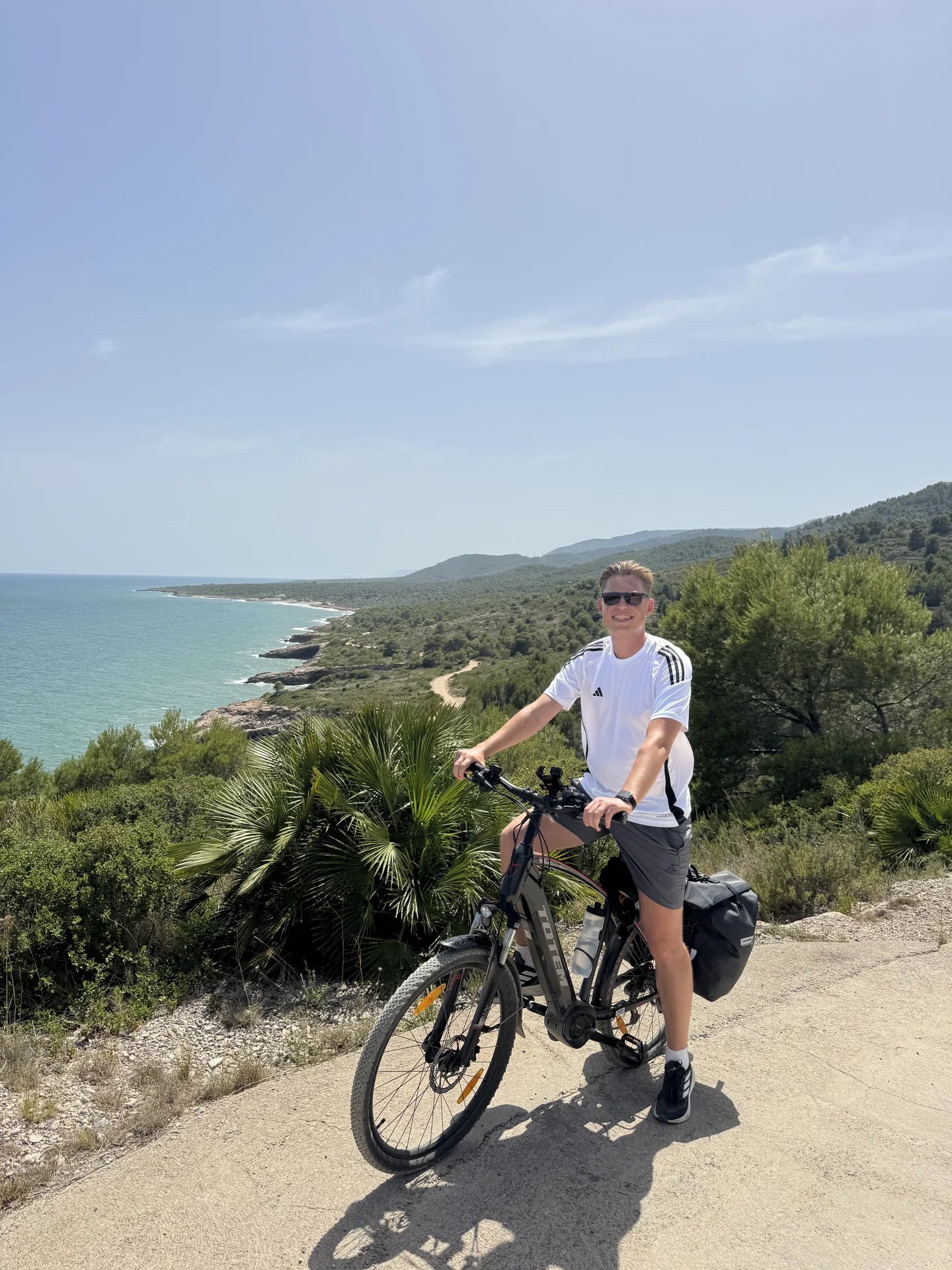 Radfahrer mit bepacktem Trekking-E-Bike mit Blick auf die Mittelmeerküste bei Valencia.